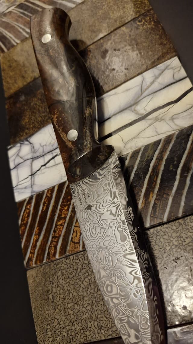 A Damascus Bran v2 laid over slabs of handle material