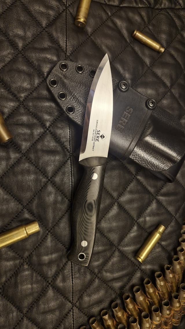 A black-handled SERE Edition Bran in its Kydex sheath on quilted leather