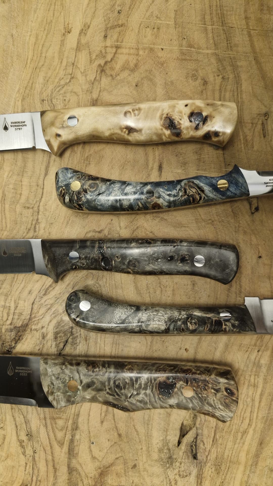 Five stabilised burl knife handles on the workbench, grain and mosaic pins visible