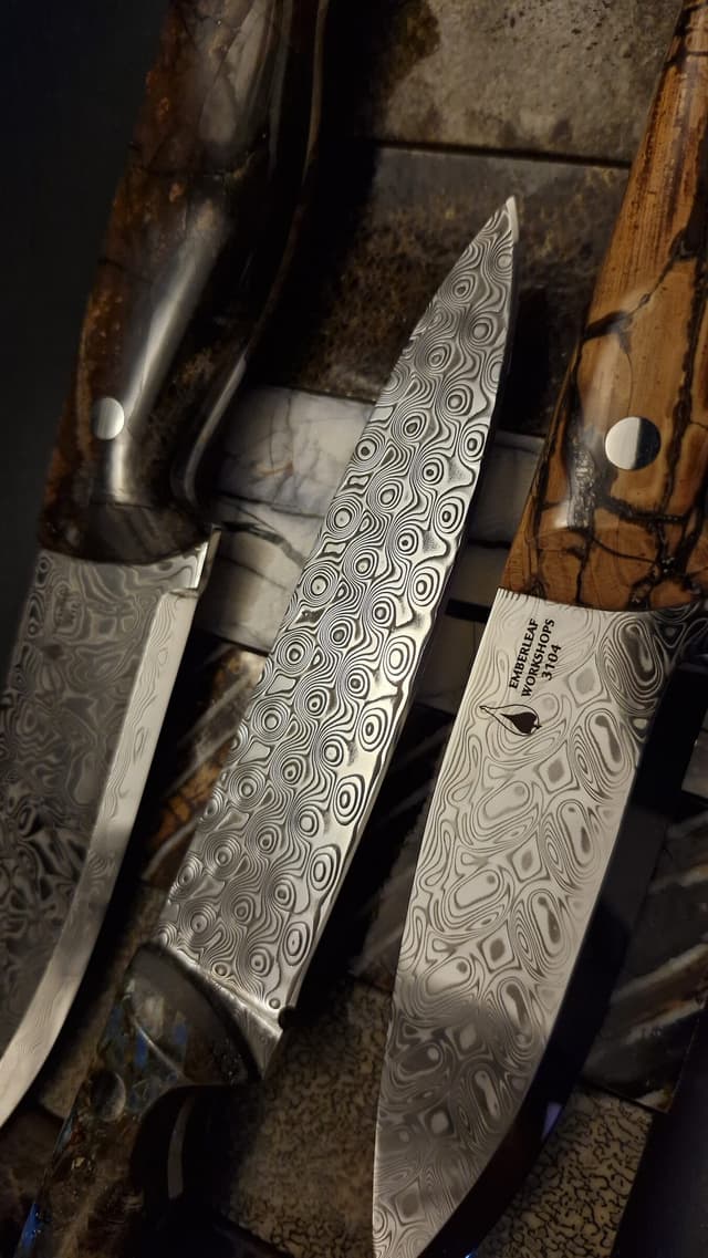 Three Damascus knives laid side by side