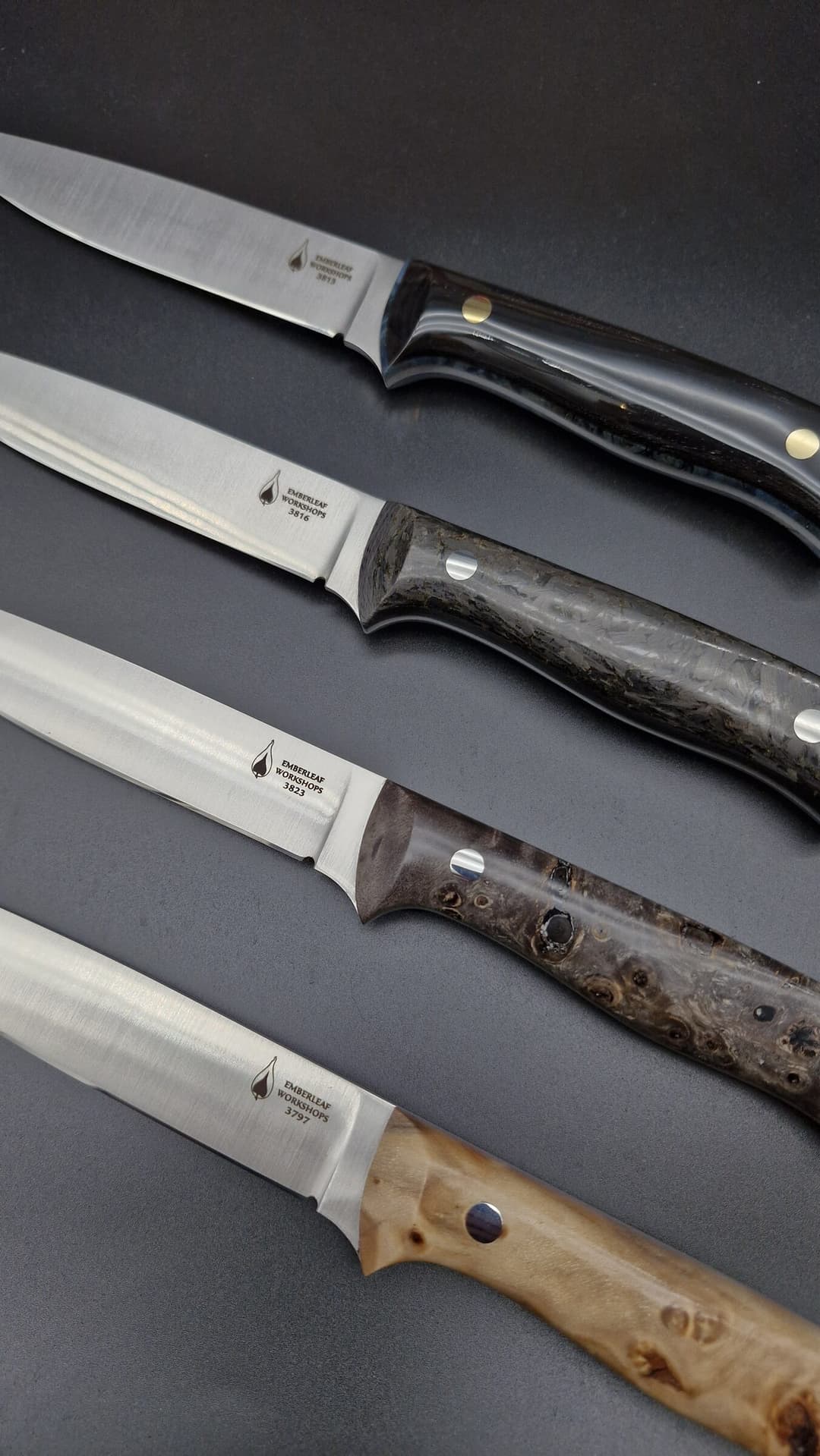 Four satin-ground blades laid parallel, grind lines and tang stamps visible