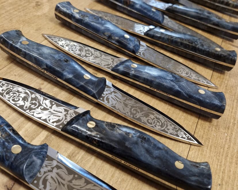 A batch of knives with floral-engraved blades and blue stabilised handles