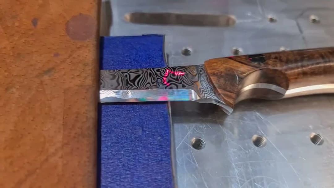 Fibre laser engraving the Emberleaf maker’s mark on a finished Damascus blade with wood handle