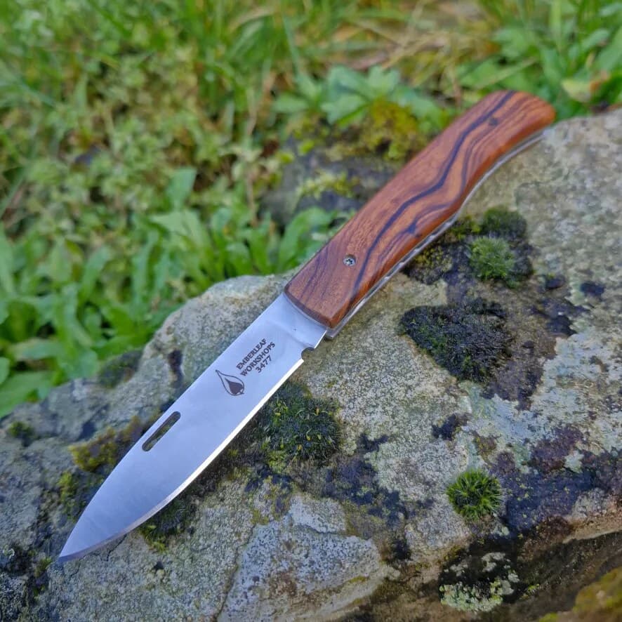 An Aquila slip joint folding knife, project 3477, open on a mossy stone