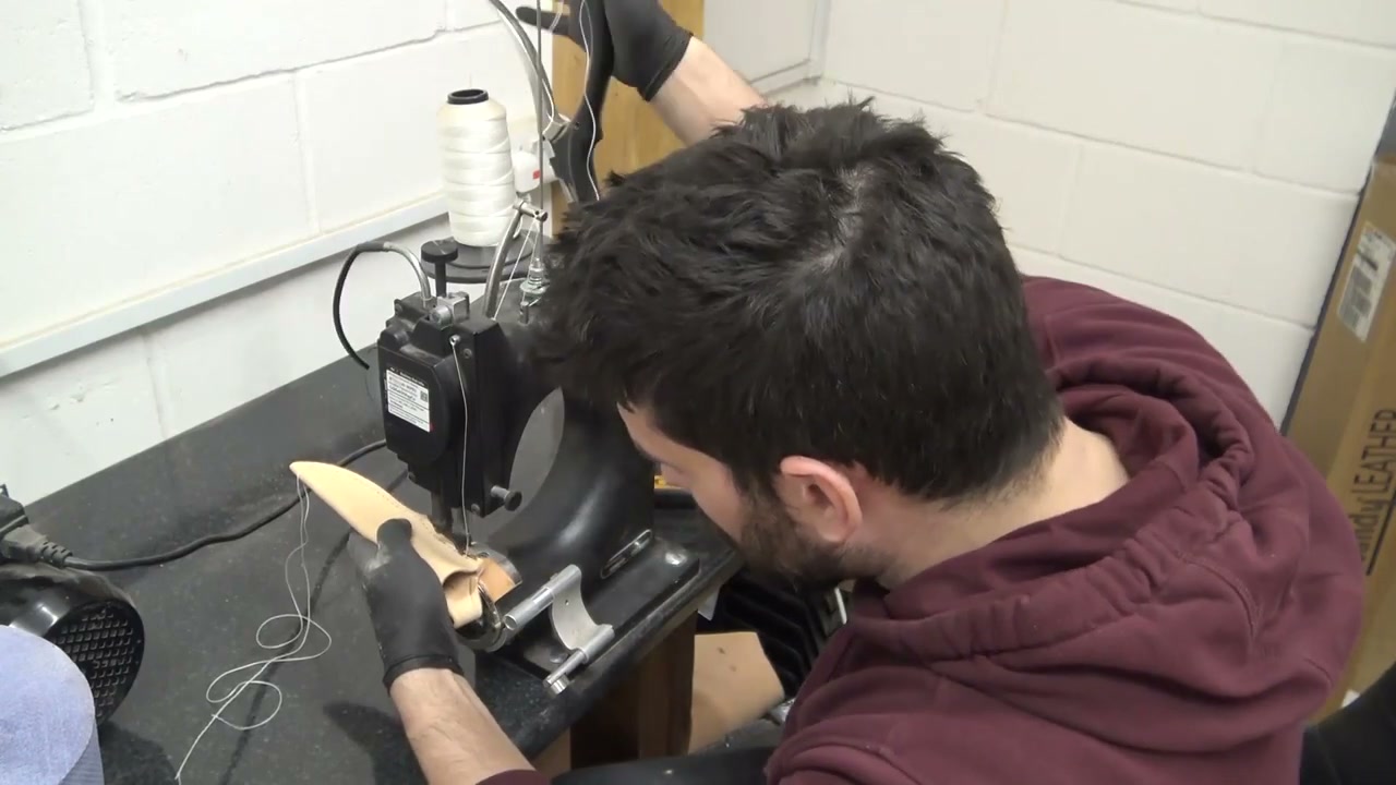 Saddle-stitching a leather sheath by hand at the bench