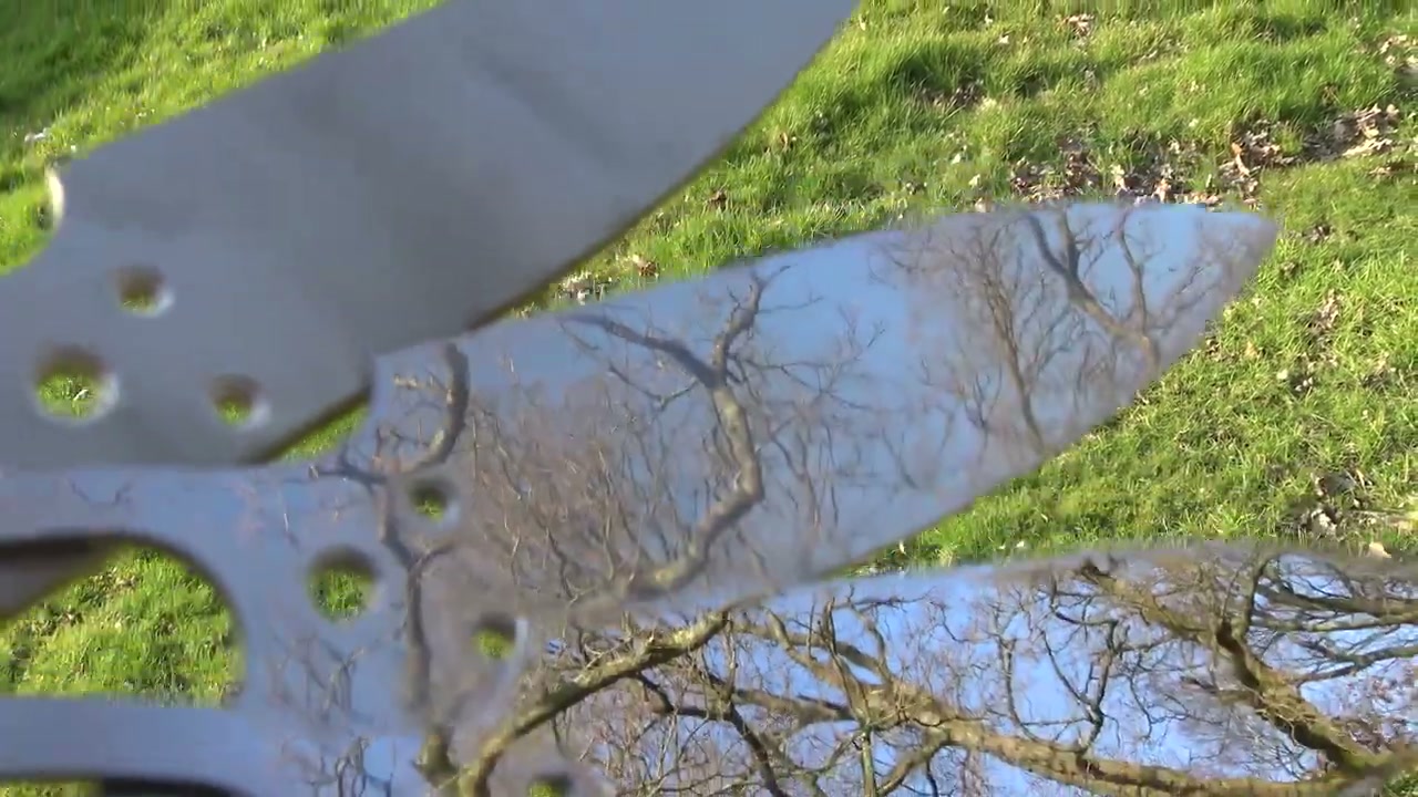 Finished mirror-polished knives reflecting the trees outside